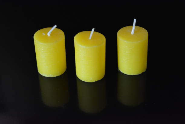 istock On black glossy background there are beautiful three round yellow candles with reflection. 1146036294