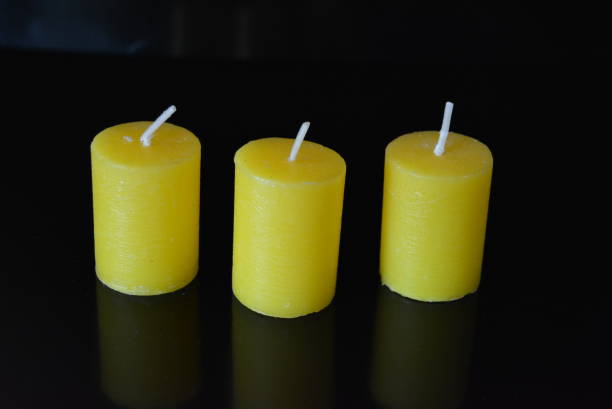 istock On black glossy background there are beautiful three round yellow candles with reflection. 1146036295