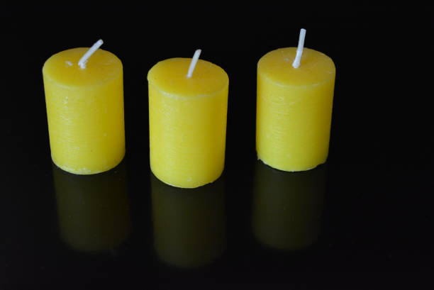 istock On black glossy background there are beautiful three round yellow candles with reflection. 1146036301
