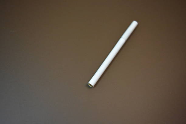 istock White thin cigarette with XS filter on matte brown background. 1146037649