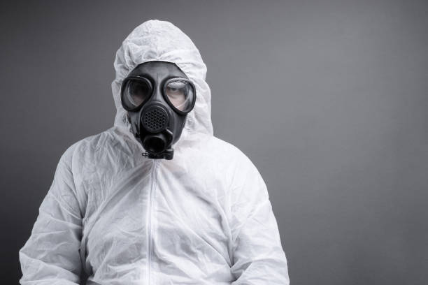 istock man with gas mask in protective overall suit against grey background 1146037662