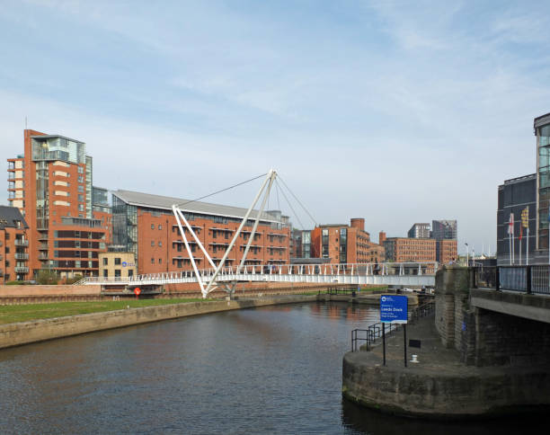 the entrance to leeds dock on the river aire with pedestrians crossing knights bridge and the royal armouries building visible - leeds england yorkshire canal museum imagens e fotografias de stock