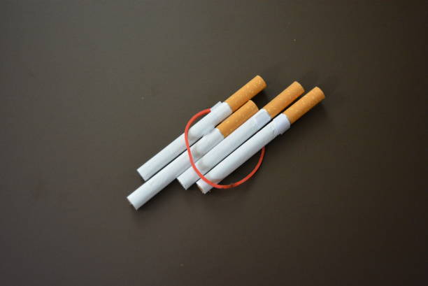 istock Regular cigarettes with tobacco lined on a brown matte table and tied with a red rubber band. 1146039260