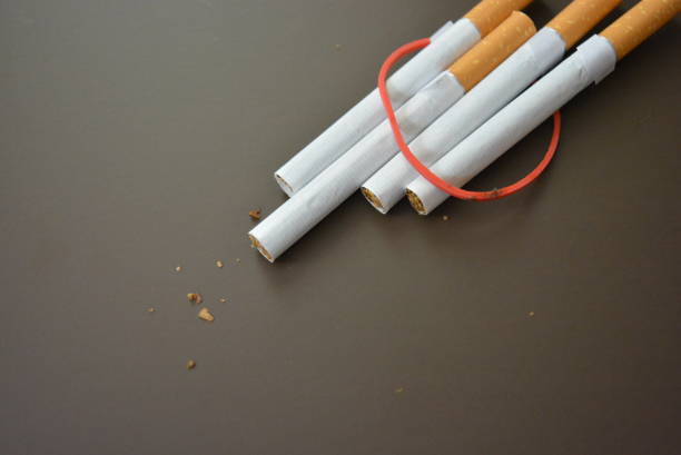 istock Regular cigarettes with tobacco lined on a brown matte table and tied with a red rubber band. 1146039265