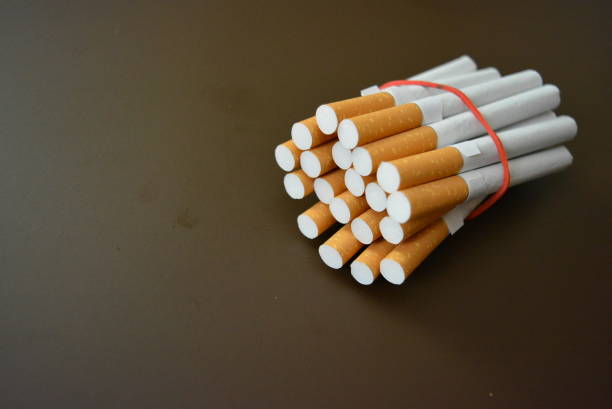 istock Cigarettes from the pack are fixed with a red rubber band on a brown matte background. 1146039288