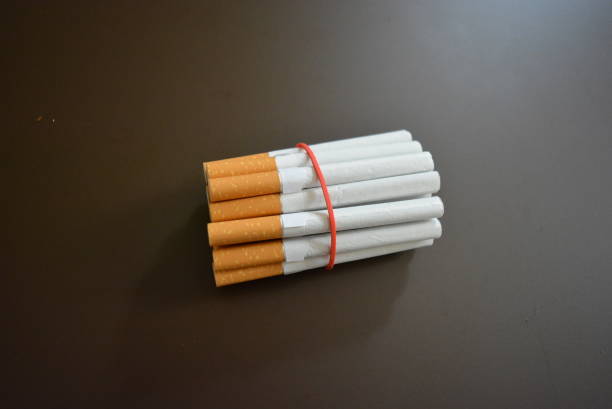 istock Cigarettes from the pack are fixed with a red rubber band on a brown matte background. 1146039302