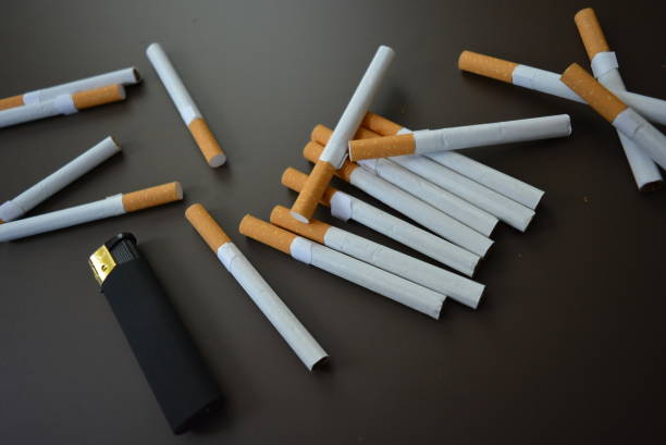 istock Beautifully laid cigarettes with a black lighter on a brown black background. 1146039490