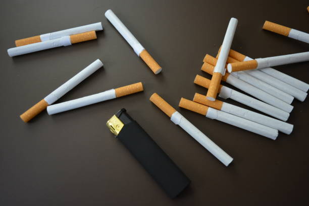 istock Beautifully laid cigarettes with a black lighter on a brown black background. 1146039496
