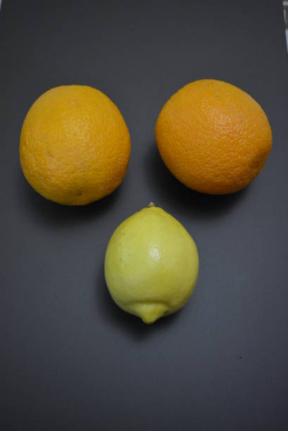 frutas frescas, dos naranjas anaranjadas con un limón amarillo sobre un interesante fondo mate. - orange portion fruit citrus fruit fotografías e imágenes de stock