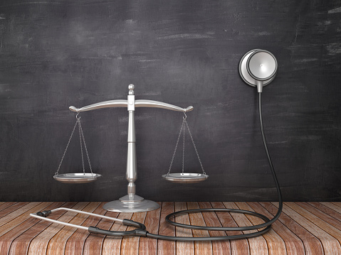 Scales of Justice with Stethoscope on Wood Floor - Chalkboard Background - 3D Rendering