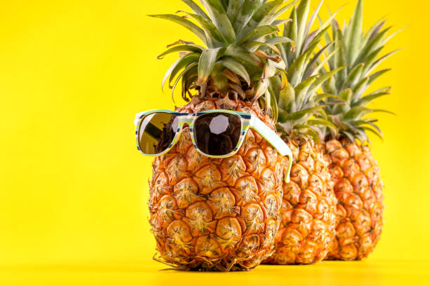 istock Creative pineapple looking up with sunglasses and shell isolated on yellow background, summer vacation beach idea design pattern, copy space close up 1146040850
