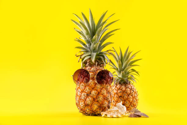 istock Creative pineapple looking up with sunglasses and shell isolated on yellow background, summer vacation beach idea design pattern, copy space close up 1146040898