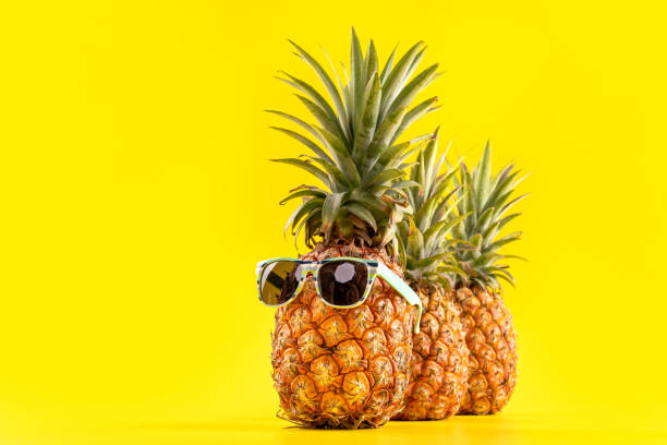 istock Creative pineapple looking up with sunglasses and shell isolated on yellow background, summer vacation beach idea design pattern, copy space close up 1146042117