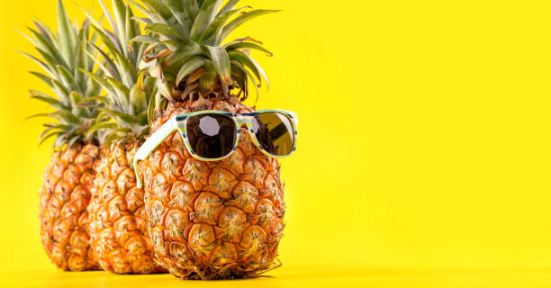 istock Creative pineapple looking up with sunglasses and shell isolated on yellow background, summer vacation beach idea design pattern, copy space close up 1146042490