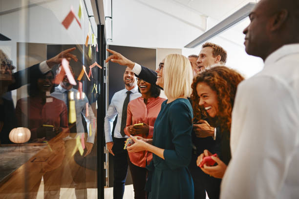 istock Smiling businesspeople brainstorming together with notes on a glass wall 1146050387