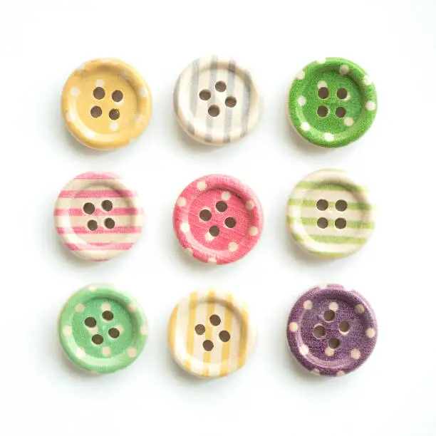 Photo of Wooden buttons with colorful stripes and colorful dots on a white background. Sewing