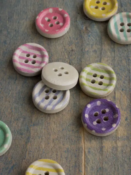 Photo of Wooden buttons with stripes of colored colors on a rustic fabric, sewing