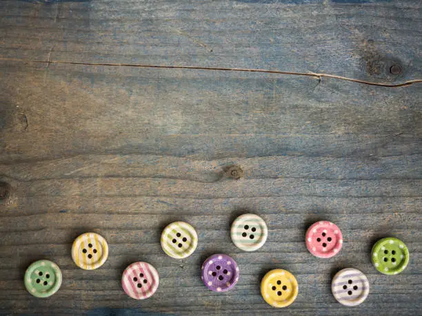 Photo of Wooden buttons with stripes of colored colors on a rustic fabric, sewing