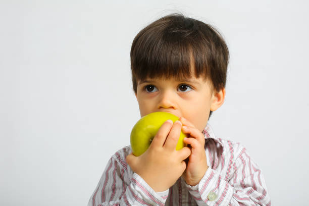 istock pretty small boy eating green apple 1146054567