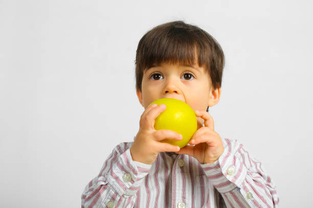 istock pretty small boy eating green apple 1146054818