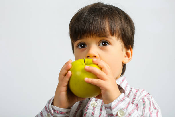 istock pretty small boy eating green apple 1146055519
