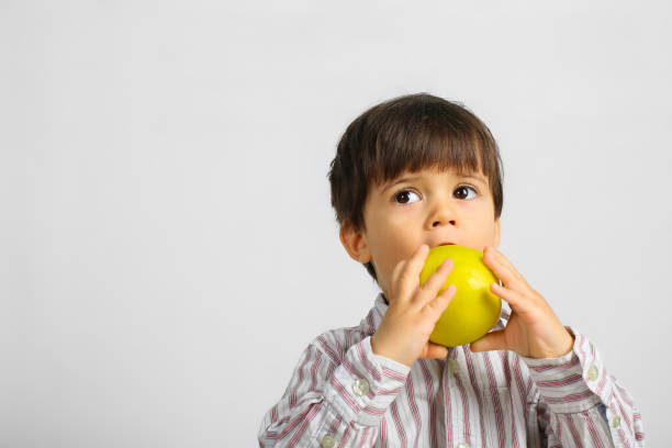 istock pretty small boy eating green apple 1146055594