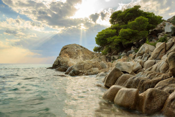 Dramatic, colorful sky and rocky edge on a wavy Koviou beach in Greece