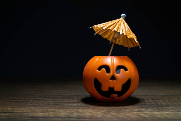 Orange Pumpkin Halloween with umbrella on wooden table in black background stock photo