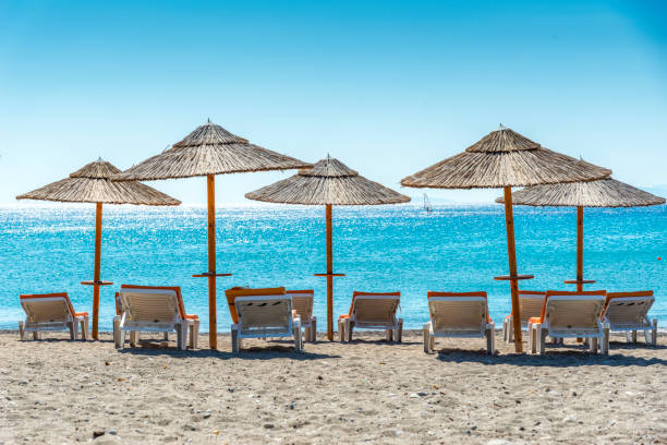 Five sun umbrellas, the sea, horizon and beach chairsHoliday in the sun, vacation background, Kos, Greece.