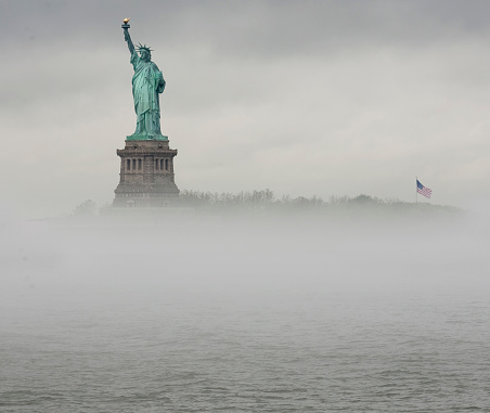 The Statue of Liberty rises above the fog on the Hudson River as seen from Jersey City, NJ.