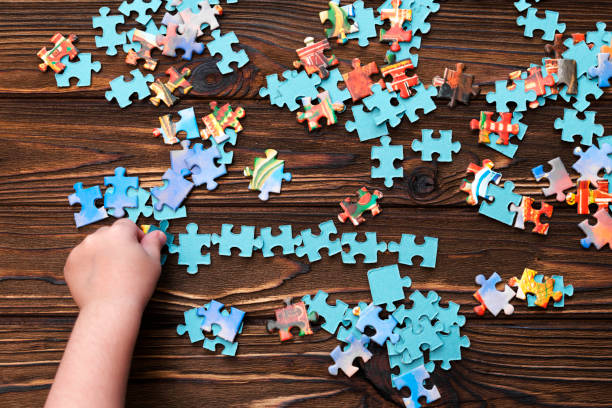 istock Puzzles, child's hand on wooden table background. 1146059696