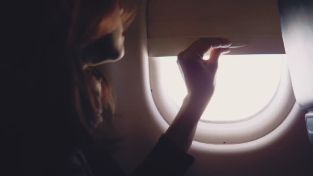 Asian tourist woman open the window on airplane