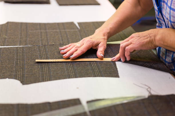 istock Female hands matching checkered pattern, constructing a suit out of luxurious wool fabric. Close up detail of garment production - selective focus. 1146061106