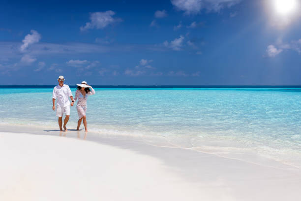 Traveler couple walks down a tropical beach
