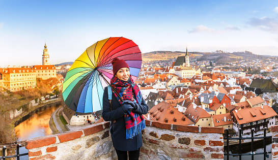 Panorama of the colorful city of Cesky Krumlov with a happy tourist with a bright umbrella in the winter