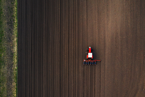 Top view of tractor planting corn seed in field, high angle view drone photography