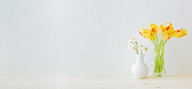 домашний интерьер с элементами декора. желтые тюльпаны в стеклянной вазе на деревянном столе - daffodil flower yellow vase стоковые фото и изображения