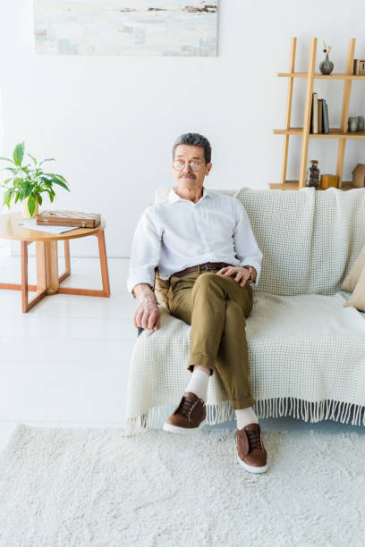 istock thoughtful senior man sitting on sofa in modern living room 1146070851