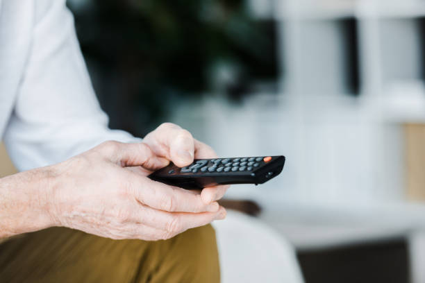 istock cropped view of senior man holding remote control in hands 1146070858