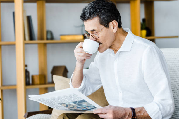 istock pensioner in glasses drinking coffee and reading newspaper at home 1146072852