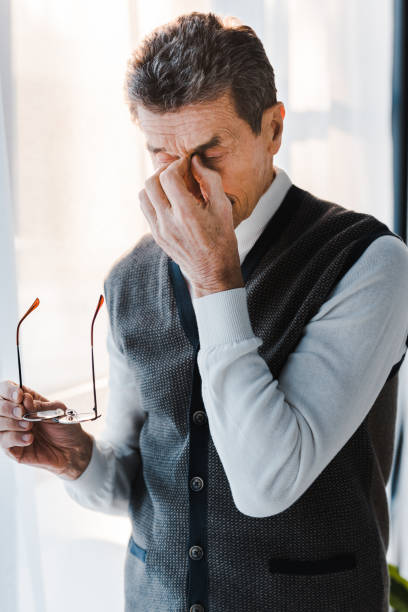 istock tired senior man with grey hair touching eyes while holding glasses 1146074764