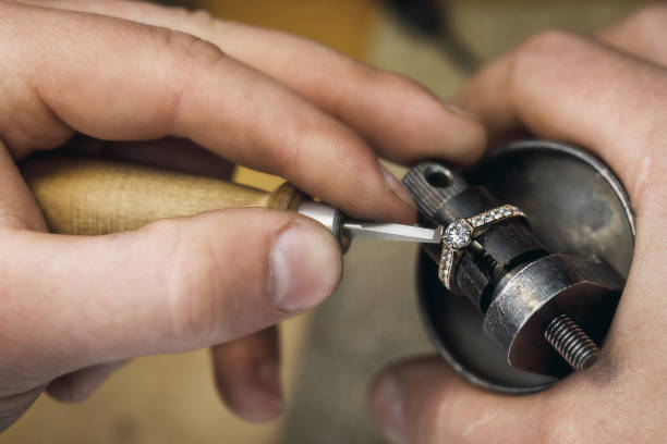 Jeweler adjusts precious stones in a gold ring, close-up Jeweler adjusts precious stones in a gold ring, close-up jewelry craftsperson craft jeweller stock pictures, royalty-free photos & images