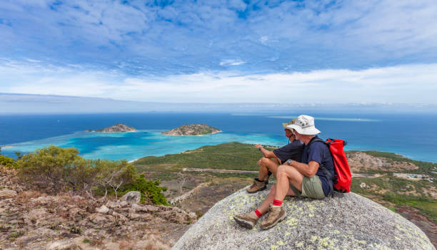 cooks lookout on lizard Island, Australia senior couple looking from spectacular view of Captain Cooks lookout from the top of Lizard Island over the Great Barrier Reef, Queensland, Australia cairns australia stock pictures, royalty-free photos & images