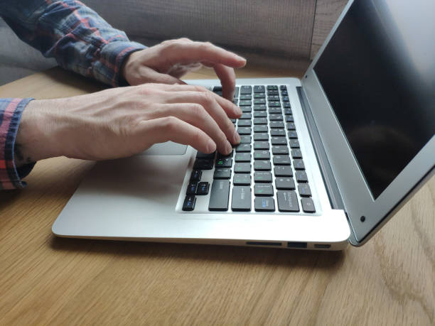 istock Closeup of male hands typing on a laptop keyboard, checking email, freelancer work 1146076259