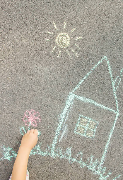 istock The child draws the house with chalk on the asphalt. Selective focus. 1146077162