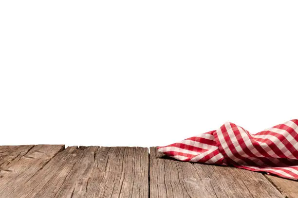 Backgrounds: eye view of an empty rustic wooden table with a crumpled red and white gingham cloth shot against white background. Ideal for background montage. Useful copy space available for text, logo or product montage. Predominant colors are brown and yellow. DSRL outdoors photo taken with Canon EOS 5D Mk II and Canon EF 24-105mm f/4L IS USM Wide Angle Zoom Lens