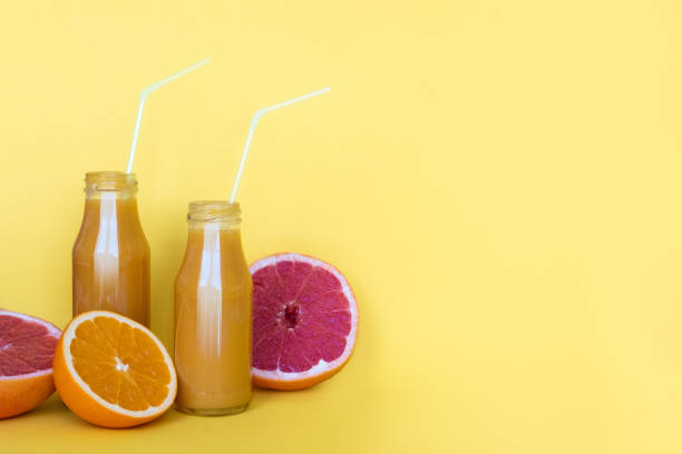 istock Fresh orange juice in bottles with oranges on yellow background. Copy space 1146078435