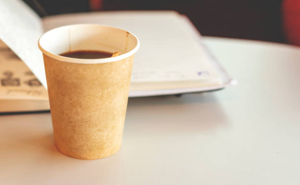 istock Coffee in a recyclable paper disposable glass with an open notebook in background 1146080596