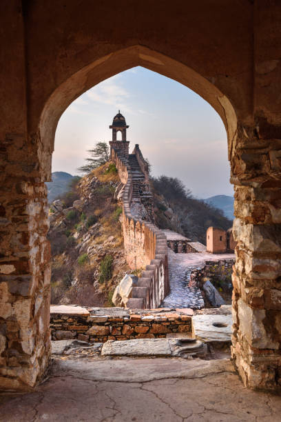 Ancient long wall with towers around Amber Fort through the arch of tower walls at morning. Rajasthan. India Ancient long wall with towers around Amber Fort through the arch of tower walls at morning. Jaipur. Rajasthan. India amber fort stock pictures, royalty-free photos & images