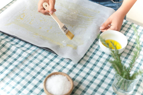 istock Boy's Hand Spreading Oil on Baking Paper 1146085694